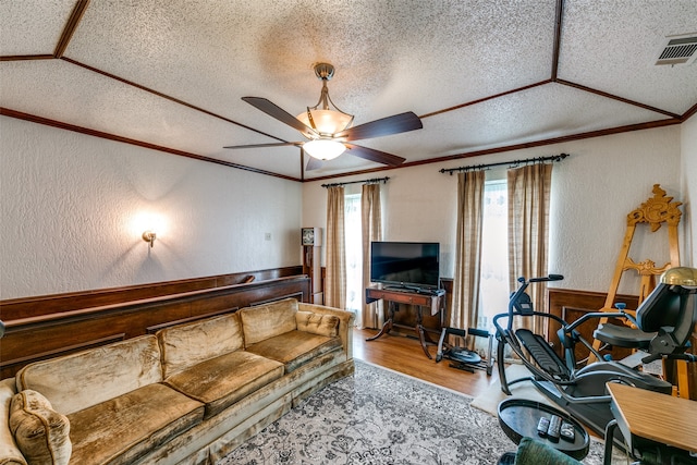 living room featuring ceiling fan, hardwood / wood-style flooring, crown molding, and a textured ceiling