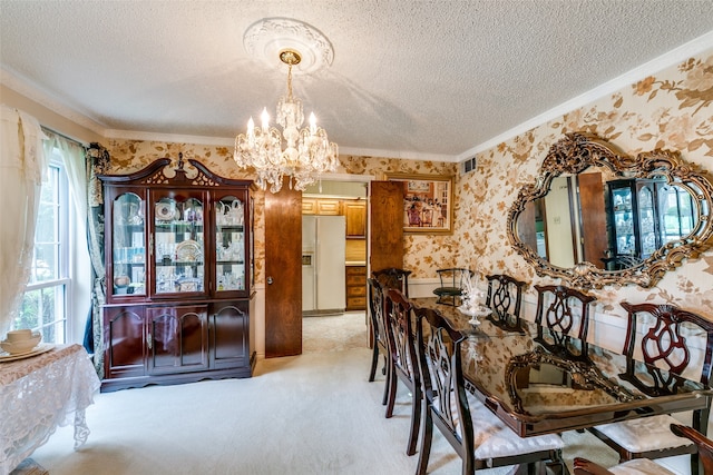 dining space featuring a textured ceiling, crown molding, an inviting chandelier, and light colored carpet