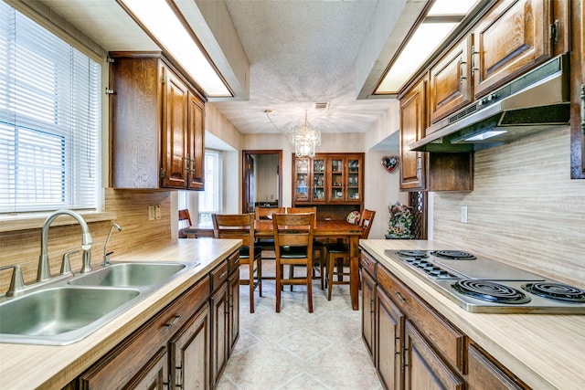 kitchen featuring a notable chandelier, stainless steel gas cooktop, sink, and a wealth of natural light