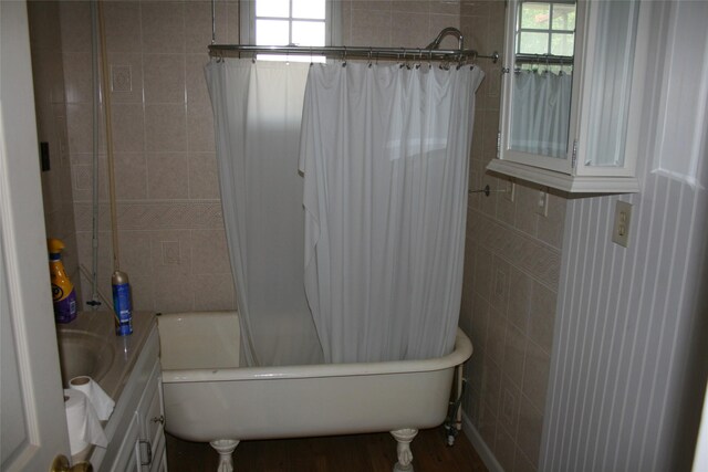 bathroom featuring shower / bathtub combination with curtain, tile walls, and hardwood / wood-style flooring