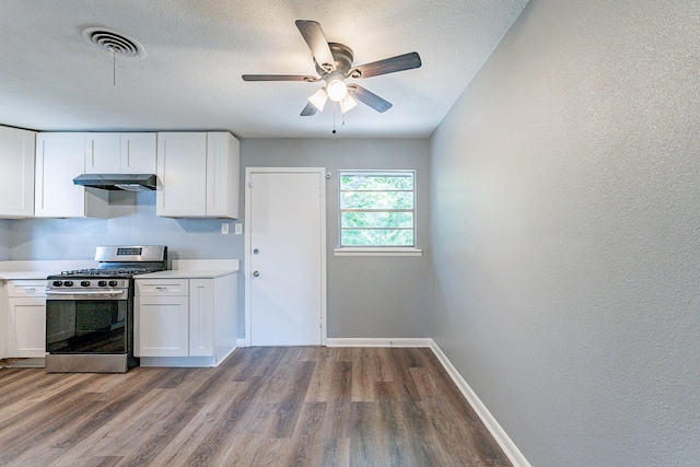 kitchen with hardwood / wood-style flooring, white cabinetry, a textured ceiling, and gas range