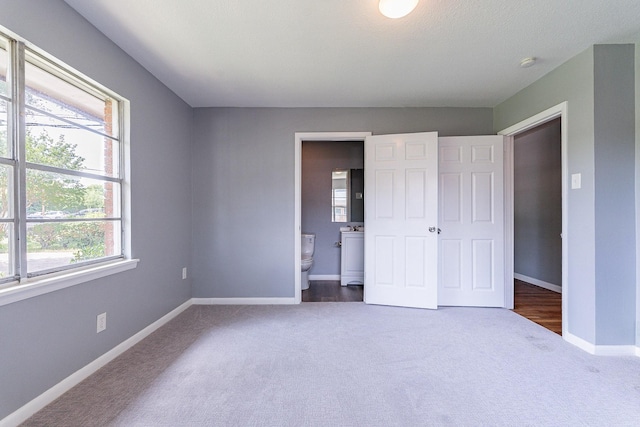 unfurnished bedroom featuring carpet floors and ensuite bath