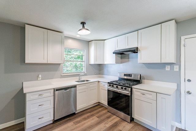 kitchen featuring appliances with stainless steel finishes, light wood-type flooring, white cabinetry, and sink