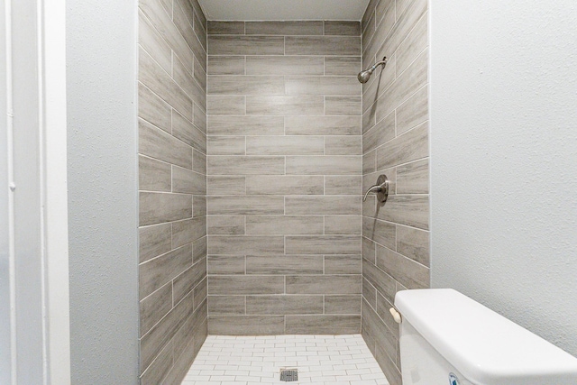 bathroom featuring a tile shower and toilet