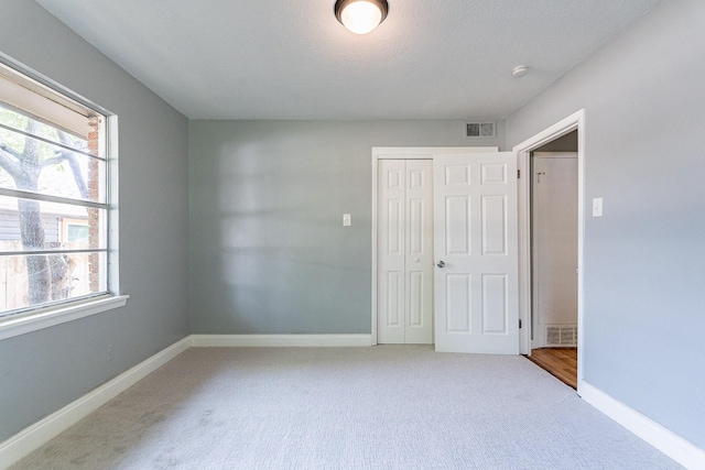 unfurnished bedroom featuring carpet floors, multiple windows, and a closet