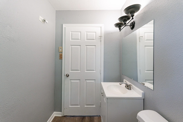 bathroom featuring hardwood / wood-style floors, vanity, toilet, and a textured ceiling