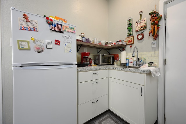 kitchen with white refrigerator, sink, and white cabinets