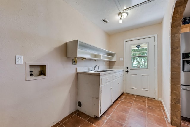 kitchen with white cabinetry, sink, light tile patterned floors, and stainless steel refrigerator with ice dispenser