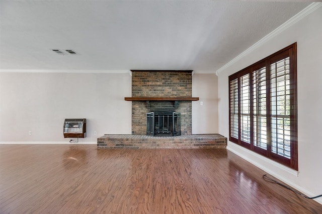 unfurnished living room featuring hardwood / wood-style flooring, crown molding, a brick fireplace, and heating unit