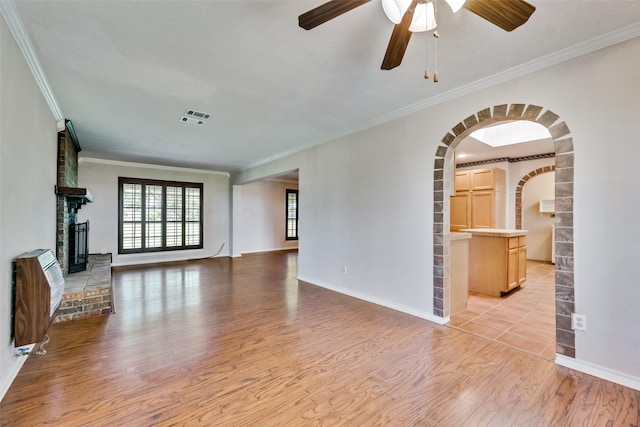 unfurnished living room featuring ceiling fan, light hardwood / wood-style floors, ornamental molding, and heating unit