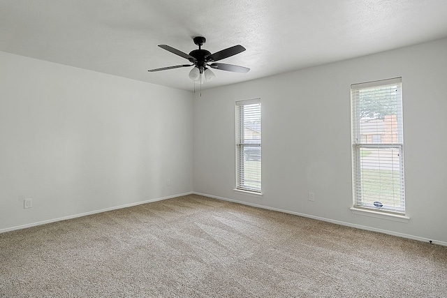 carpeted empty room featuring ceiling fan and plenty of natural light