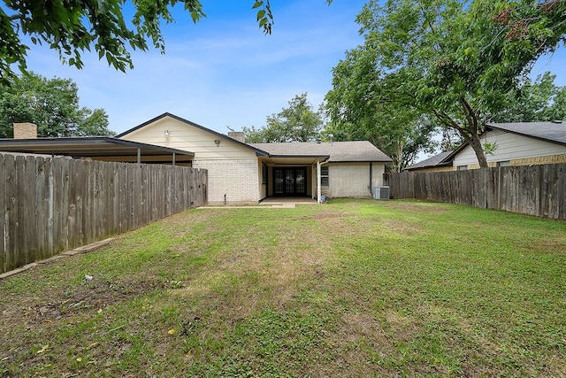 rear view of house with a yard and central AC unit