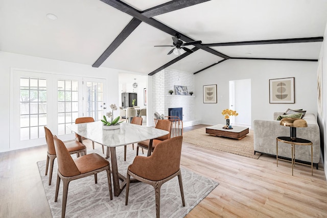 dining area with light wood-type flooring, vaulted ceiling with beams, a brick fireplace, and ceiling fan