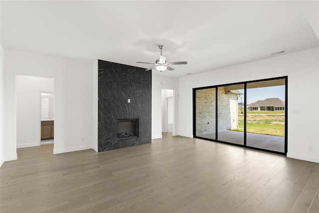 unfurnished living room with a fireplace, visible vents, ceiling fan, wood finished floors, and baseboards