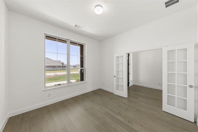 unfurnished room featuring french doors, wood finished floors, visible vents, and baseboards