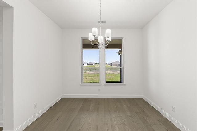 unfurnished dining area with an inviting chandelier, baseboards, visible vents, and wood finished floors