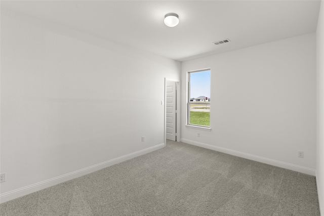 spare room with carpet floors, visible vents, and baseboards