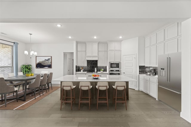 kitchen with hardwood / wood-style floors, stainless steel appliances, a center island with sink, and white cabinets