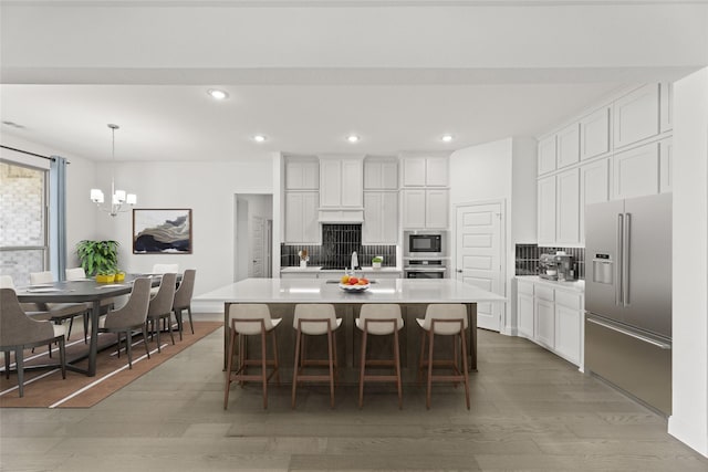 kitchen featuring white cabinets, stainless steel appliances, light countertops, light wood-style floors, and backsplash