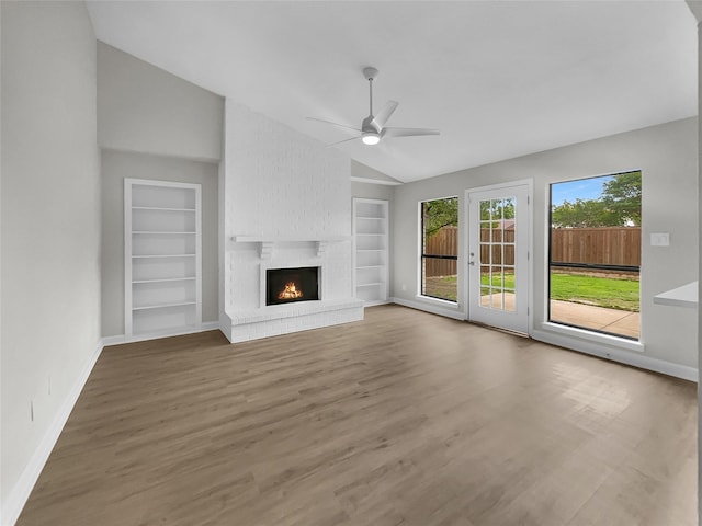 unfurnished living room featuring a fireplace, ceiling fan, vaulted ceiling, and built in features