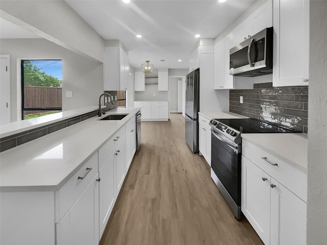 kitchen featuring white cabinets, stainless steel appliances, decorative backsplash, sink, and light hardwood / wood-style flooring