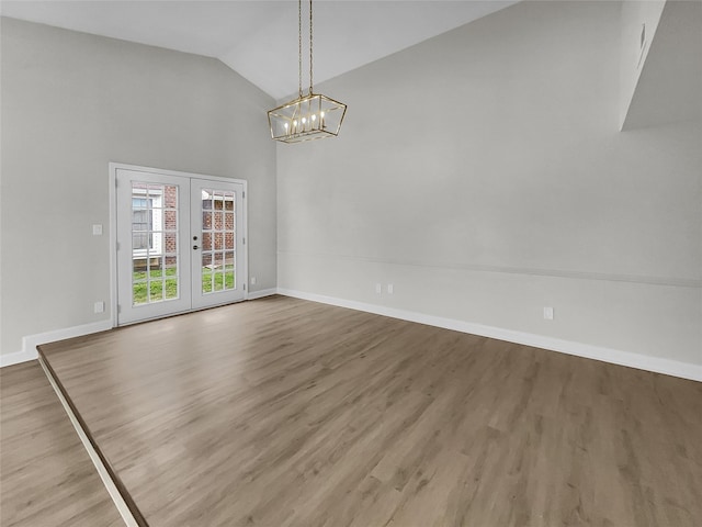 spare room featuring french doors, lofted ceiling, a chandelier, and wood-type flooring