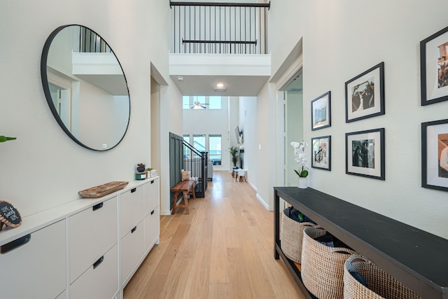 hallway featuring light wood-type flooring and a towering ceiling