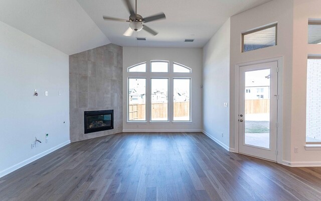 unfurnished living room featuring high vaulted ceiling, dark hardwood / wood-style flooring, a tiled fireplace, and ceiling fan