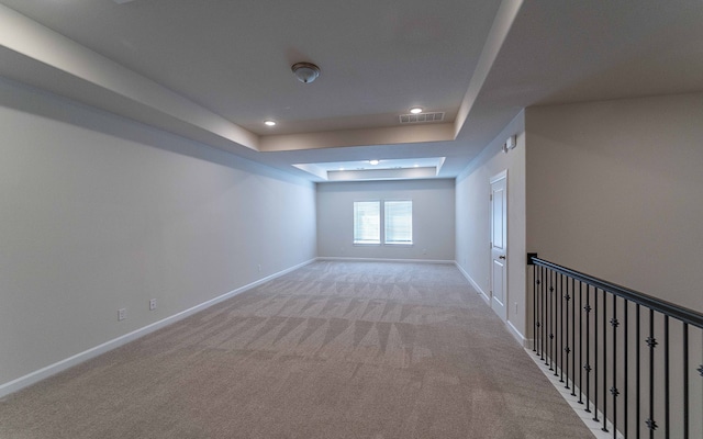 carpeted spare room featuring a tray ceiling