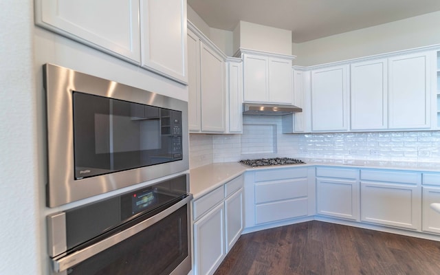 kitchen with stainless steel appliances, white cabinetry, backsplash, and dark hardwood / wood-style floors