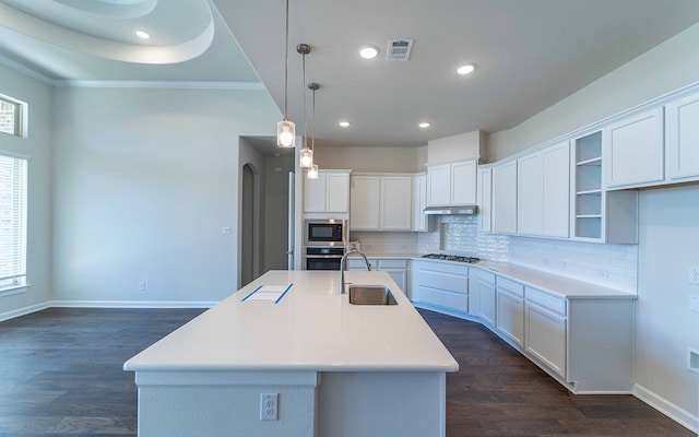 kitchen featuring dark hardwood / wood-style floors, hanging light fixtures, a kitchen island with sink, white cabinets, and appliances with stainless steel finishes