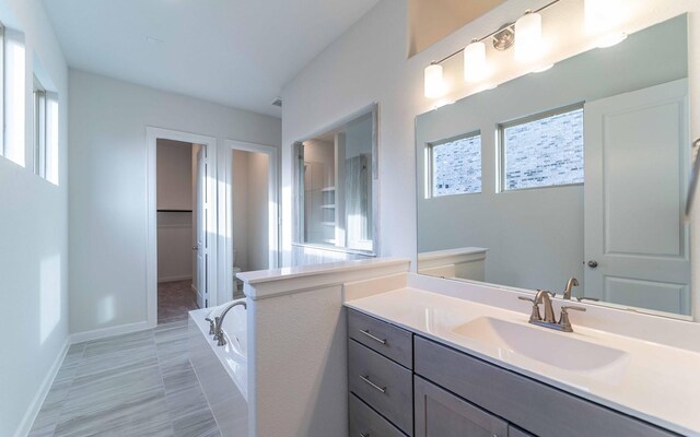 bathroom featuring tile flooring, vanity, and a washtub