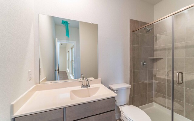 bathroom featuring vanity with extensive cabinet space, an enclosed shower, and toilet