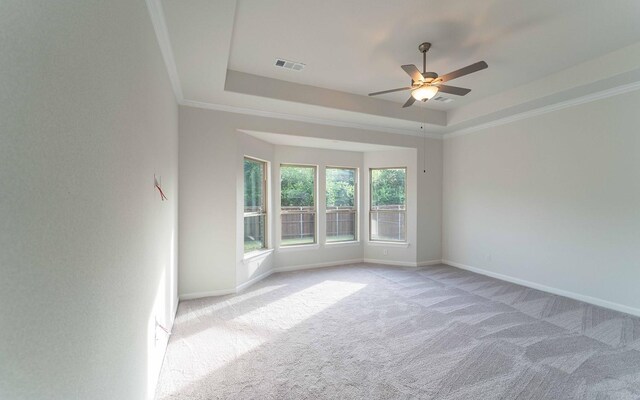 carpeted empty room with ceiling fan, a raised ceiling, and crown molding