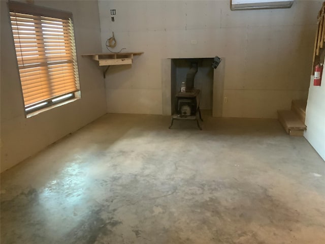 interior space with an AC wall unit, a wood stove, and concrete floors