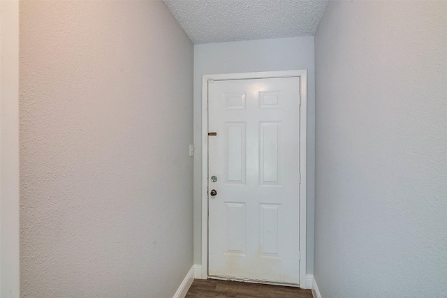 doorway with dark hardwood / wood-style floors and a textured ceiling