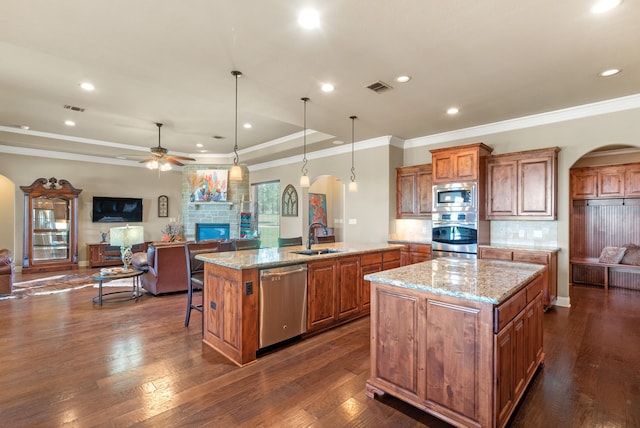 kitchen with pendant lighting, stainless steel appliances, a large island with sink, and dark wood-type flooring