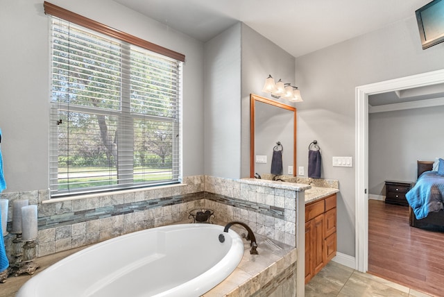 bathroom featuring hardwood / wood-style floors, plenty of natural light, tiled tub, and vanity