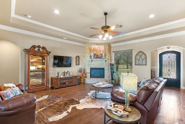 living room with a raised ceiling, dark hardwood / wood-style flooring, and ornamental molding