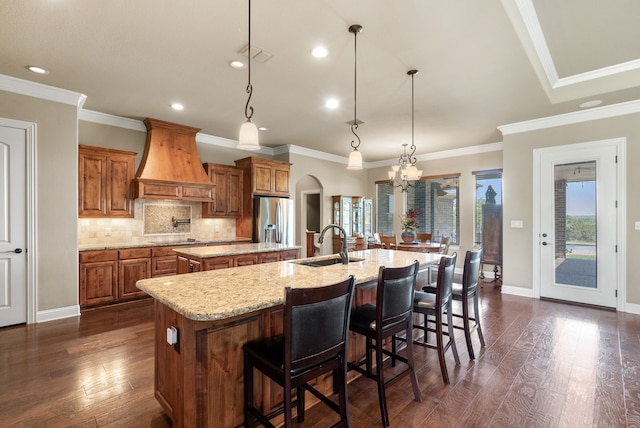 kitchen featuring sink, hanging light fixtures, dark hardwood / wood-style flooring, stainless steel refrigerator with ice dispenser, and a spacious island