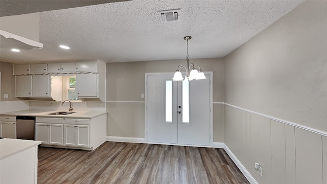 kitchen with sink, white cabinetry, hanging light fixtures, hardwood / wood-style floors, and a textured ceiling