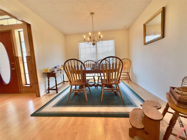 dining area with hardwood / wood-style flooring, a textured ceiling, and an inviting chandelier