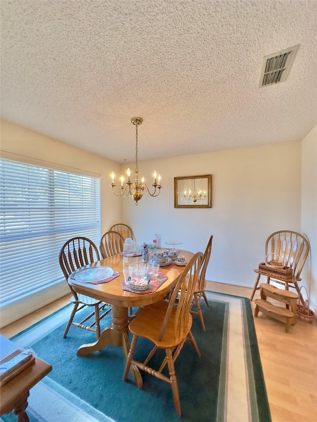 dining space featuring a chandelier, wood-type flooring, and a textured ceiling