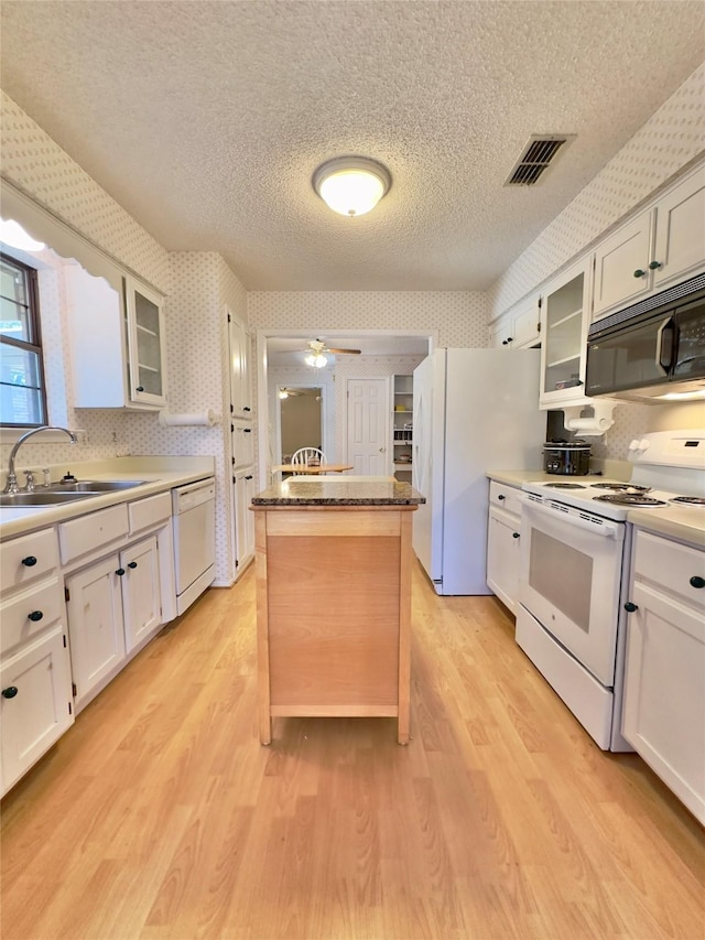 kitchen featuring white cabinets, white appliances, a center island, and sink