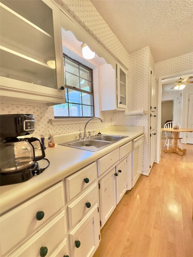 kitchen featuring ceiling fan, dishwasher, sink, light hardwood / wood-style flooring, and a textured ceiling