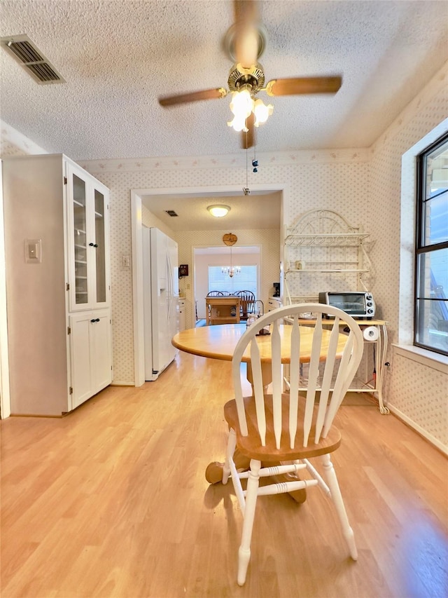 dining space featuring a fireplace, light wood-type flooring, and a textured ceiling