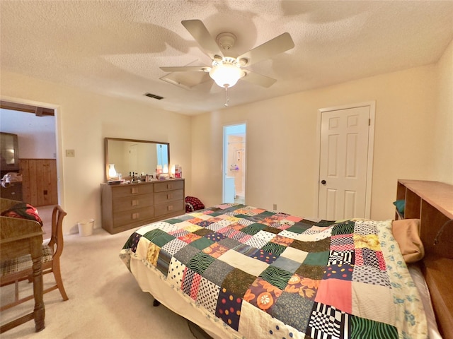 carpeted bedroom featuring a textured ceiling, ensuite bathroom, and ceiling fan