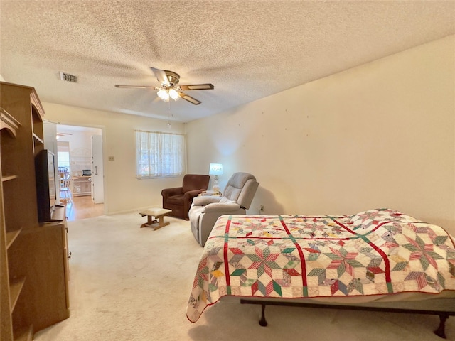 carpeted bedroom featuring ceiling fan and a textured ceiling