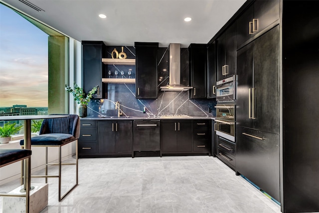 kitchen with wall chimney range hood, stainless steel appliances, sink, tasteful backsplash, and light tile floors