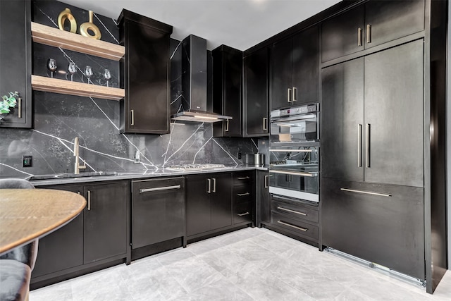 kitchen with multiple ovens, wall chimney range hood, light tile floors, and built in refrigerator